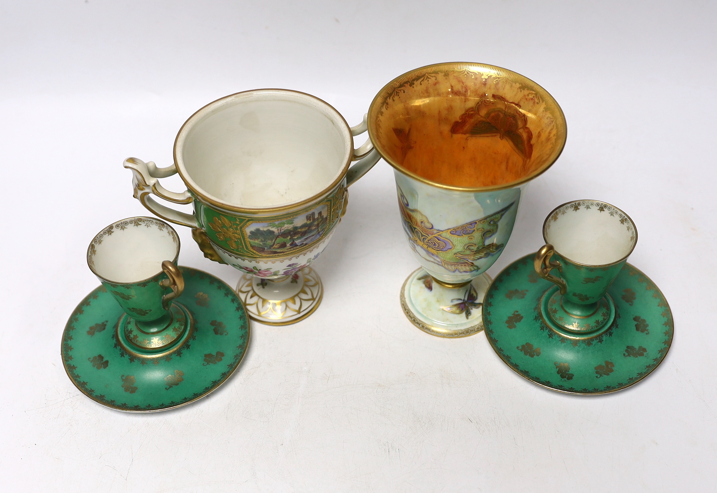 A Continental porcelain twin handled trophy cup with landscape vignettes, together with a pair of Continental liqueur cups and dishes, and a Wedgwood butterfly lustre posy vase, design number Z4832, vase 13.5cm high (4)